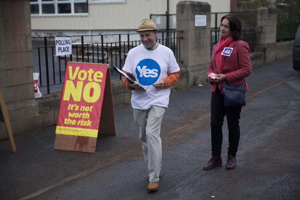 A Yes campaigner and a No campaigner stand outside a polling place in Edinburgh, Scotland, Thursday, Sept. 18, 2014. Polls have opened across Scotland in a referendum that will decide whether the country leaves its 307-year-old union with England and becomes an independent state. (AP Photo/Matt Dunham)