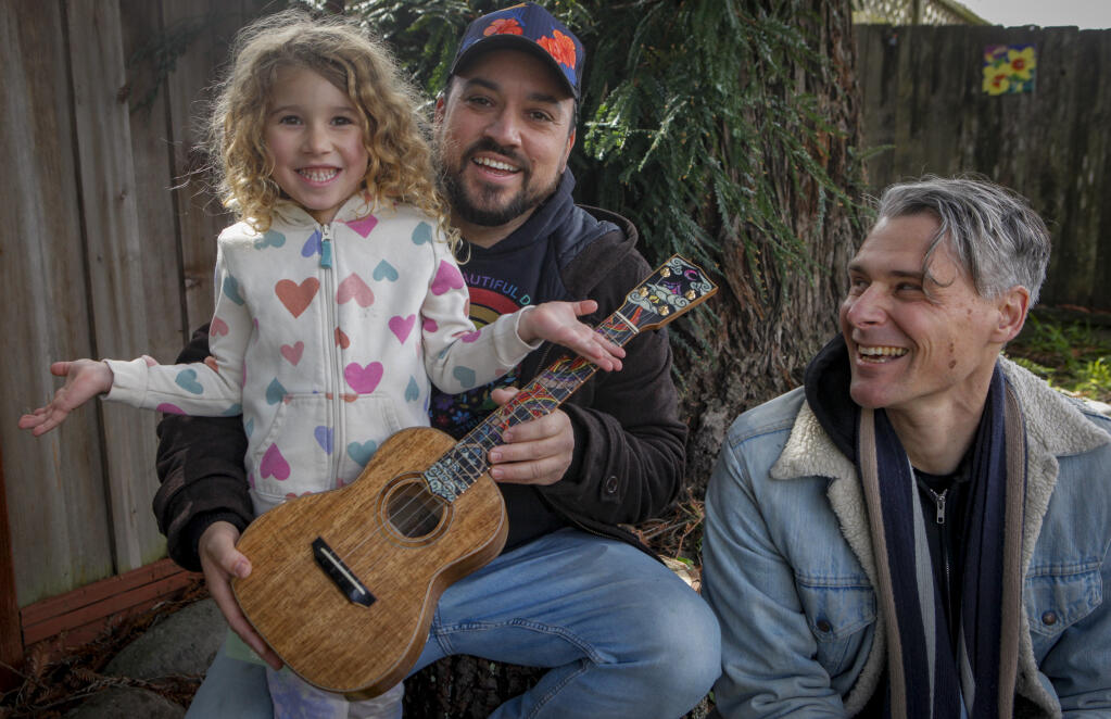 Kawai Carvalho (center) holding oldest child Kaipo Coast (left) with Gio Benedetti (right). They recently collaborated to create a handmade ukulele that will be auctioned off at the Live Oak School fundraiser where both of their children attend school. Kaipo is in kindergarten. Monday, February 27, 2023. (CRISSY PASCUAL/ARGUS-COURIER STAFF)
