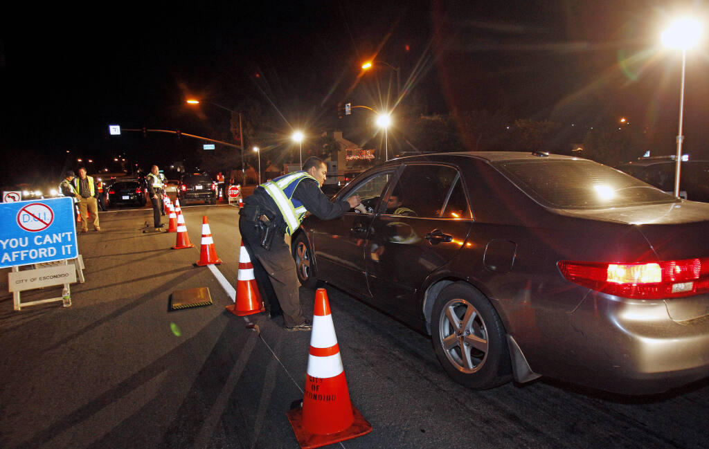 FILE - Police officers check drivers at a sobriety checkpoint in Escondido, Calif., on Dec. 16, 2011. Prosecutors in seven California counties said Wednesday, Dec. 22, 2021, that they are seeing a rapid rise in deadly DUI crashes in their jurisdictions just as people begin socializing for the holidays and planning New Year's Eve outings. (AP Photo/Lenny Ignelzi, File)