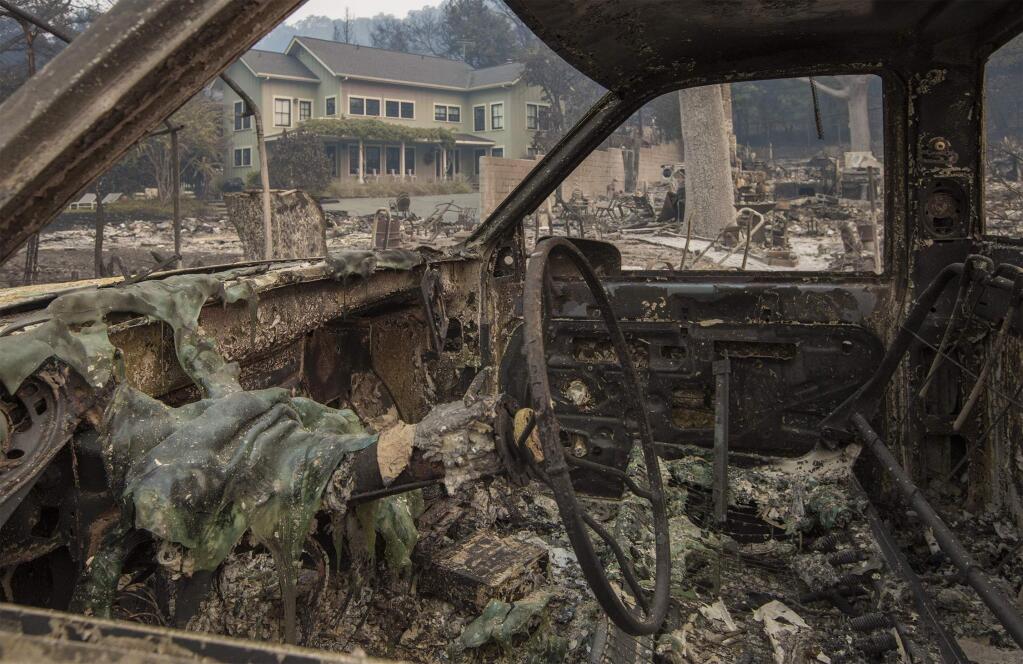 One of the homes that was spared viewed through the carcass of a burnt-out vehicle. More devastated homes in Glen Ellen - on Warm Springs Road, Sylvia Drive, Highway 12 and London Ranch Road. (Photo by Robbi Pengelly/Index-Tribune)
