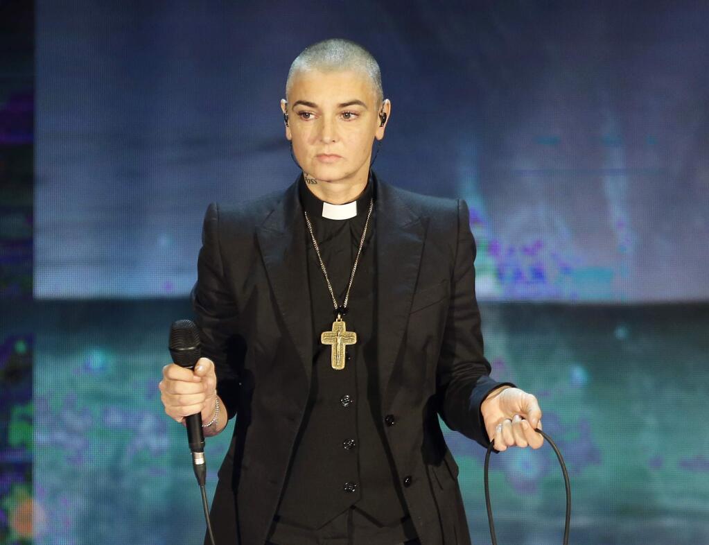 FILE - In this Oct. 5, 2014 file photo, Irish singer Sinead O'Connor performs during the Italian State RAI TV program 'Che Tempo che Fa', in Milan, Italy. Arsenio Hall sued O'Connor for libel on Thursday, May 5, 2016, in Los Angeles Superior Court over a Facebook post by the singer in which she accused the comedian of furnishing drugs to Prince, who died on April 21, 2016. Investigators are looking into whether he overdosed. (AP Photo/Antonio Calanni, File)