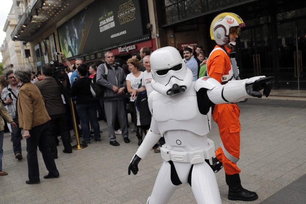 A man dressed as a Stormtrooper poses for photographers next to people queuing to attend the steaming of Star Wars Celebration from the Anaheim Convention Center in California, in Paris, France, Thursday, April 16, 2015. (AP Photo/Christophe Ena)