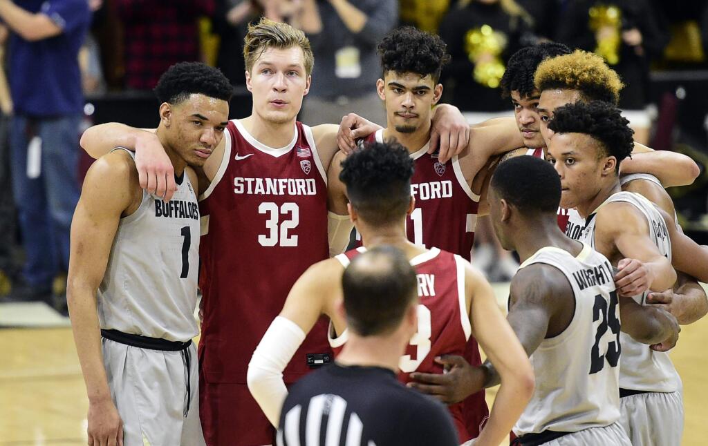 Colorado and Stanford players gather to say a prayer for Stanford's Oscar da Silva, who had hit his head on the floor in a collision during the second half Saturday, Feb. 8, 2020, in Boulder, Colo. (AP Photo/Cliff Grassmick)