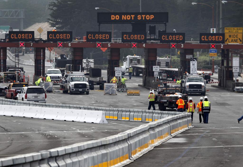 FILE - In this Jan 10, 2015, file photo, a road crew works at the toll plaza while a movable median barrier is installed on the Golden Gate Bridge in San Francisco. Northern California's iconic Golden Gate Bridge will cost southbound motorists and additional quarter to cross starting July 1, 2018. The toll hike will mean some drivers will pay as much as $8 US Dollars to travel from Marin County to San Francisco. (Paul Chinn/San Francisco Chronicle via AP, File)
