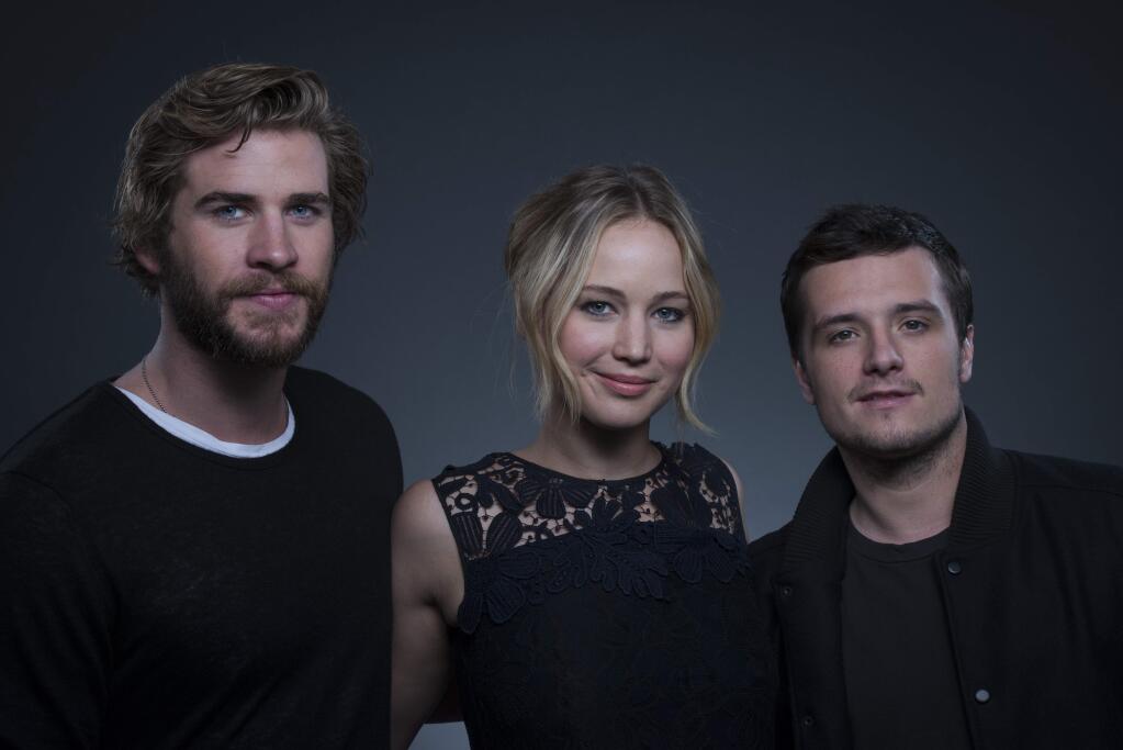 Co-starring in 'The Hunger Games: Mockingjay - Part 1' from left, actors Liam Hemsworth, Jennifer Lawrence and Josh Hutcherson pose for a portrait on Saturday, Nov. 15, 2014 in New York. (Photo by Drew Gurian/Invision/AP)