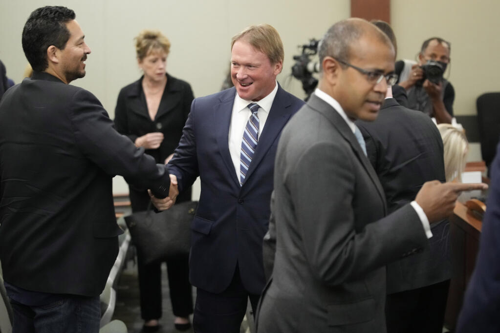 Jon Gruden, center, appears in court Wednesday, May 25, 2022, in Las Vegas. A Nevada judge heard a bid Wednesday by the National Football League to dismiss former Las Vegas Raiders coach Jon Gruden's lawsuit accusing the league of a "malicious and orchestrated campaign" including the leaking of offensive emails ahead of his resignation last October. (AP Photo/John Locher)