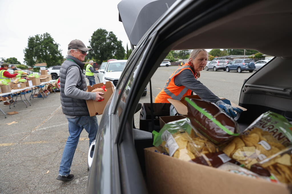 Volunteers Kristen Wood, right, and Steve Hade pack food into a client’s vehicle during a Redwood Empire Food Bank distribution event at the Santa Rosa Veterans Memorial Building, Thursday, May 25, 2023.  (Christopher Chung / The Press Democrat file)