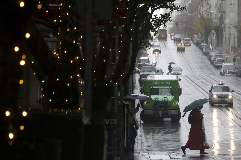 A woman carries an umbrella as she crosses California Street in San Francisco, Friday, Dec. 19, 2014. (AP Photo/Jeff Chiu)