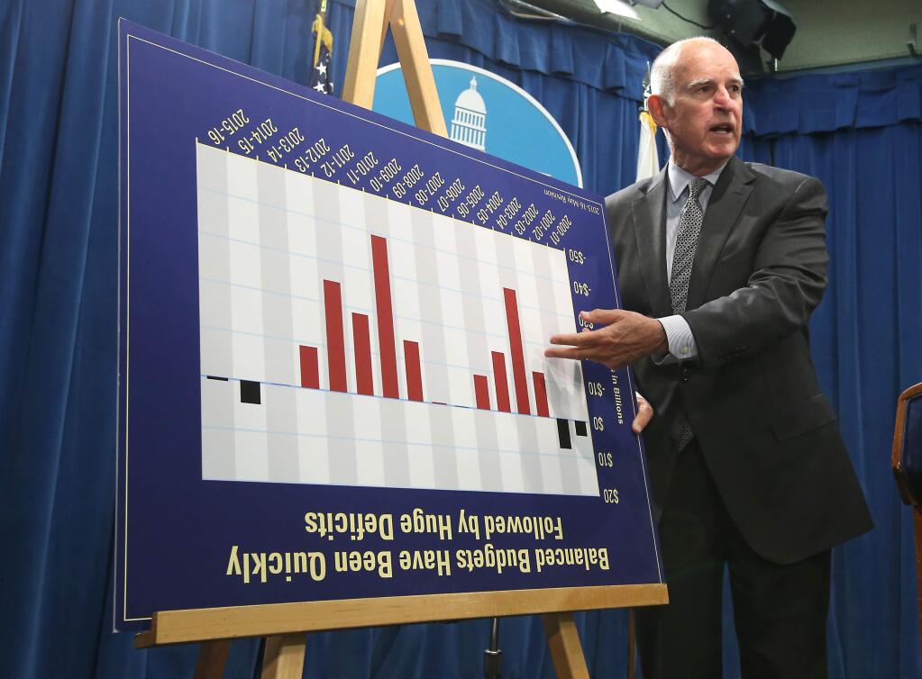Gov. Jerry Brown jokes with reporters by turning a budget chart upside as he discusses his revised state budget plan during a news conference last week at the Capitol. (RICH PEDRONCELLI / Associated Press)