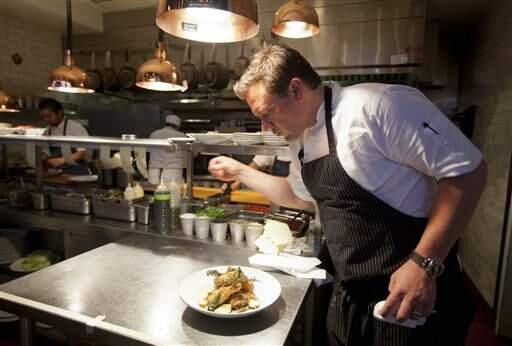 In this photo taken Monday, Oct. 29, 2012, chef Tyler Florence puts a finishing touch to his fried chicken dish in the kitchen at his Wayfare Tavern in San Francisco. (AP Photo/Eric Risberg)