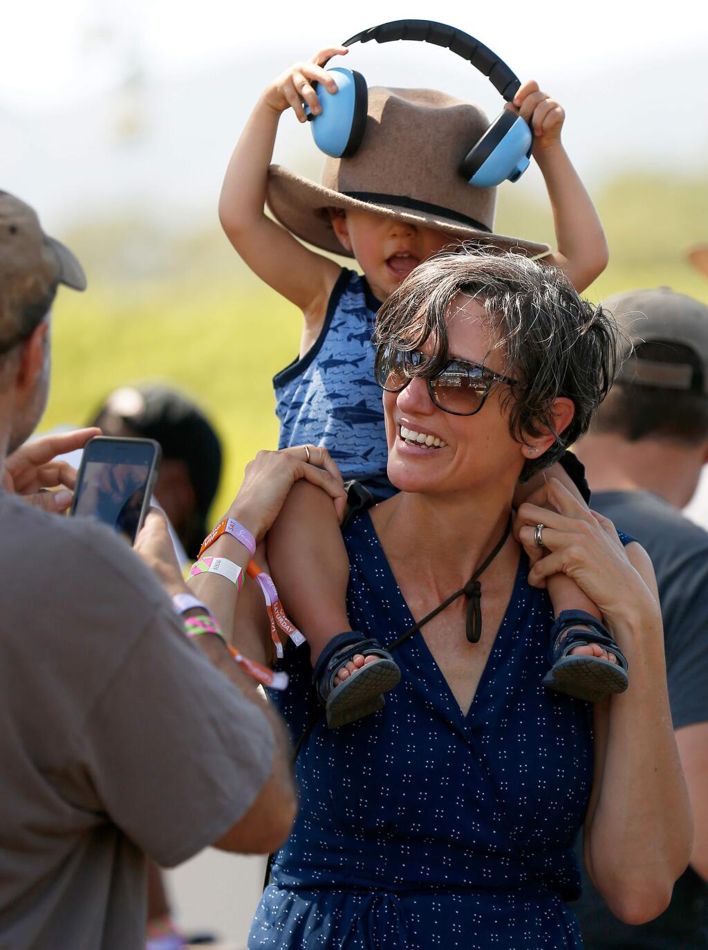 Catherine Long of Oakland carries her son Monk Kasper, 2, as he tries to don ear protection while wearing her hat, as they listen to Mandolin Orange performing on stage, during the first day of the Sonoma Harvest Music Festival at B.R. Cohn Winery and Olive Oil Company, in Glen Ellen, California, on Saturday, September 14, 2019. (Alvin Jornada / The Press Democrat)