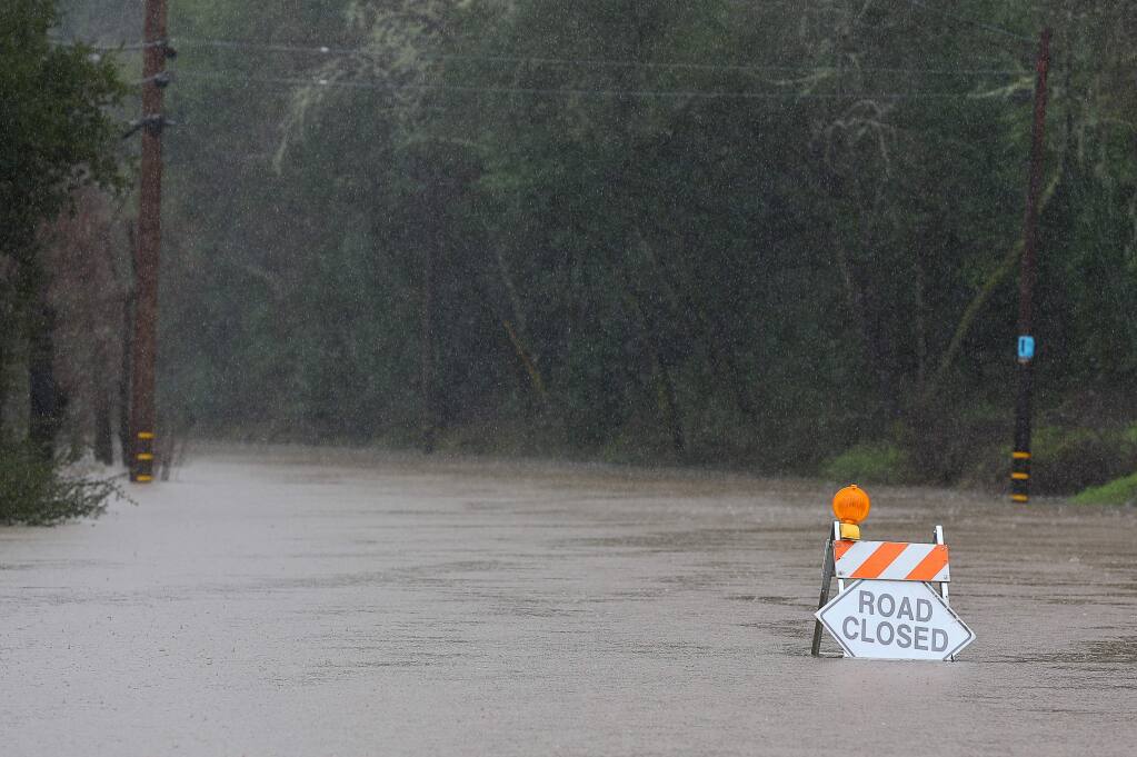 Water envelopes a road closure sign along Alexander Valley Road, in Healdsburg on Tuesday, February 26, 2019. (Christopher Chung/ The Press Democrat)