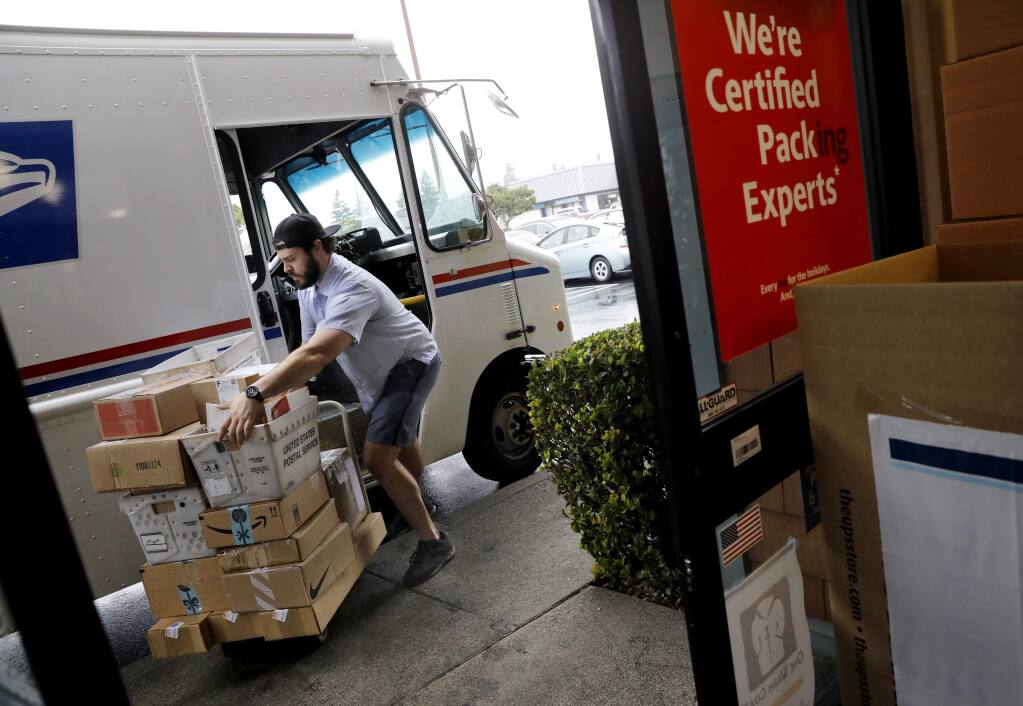 U.S. Postal worker John Sabia collects boxes to be shipped through the U.S. Postal Service at the UPS Store on W. College Ave. in Santa Rosa on Tuesday, December 18, 2018. (Beth Schlanker/The Press Democrat)