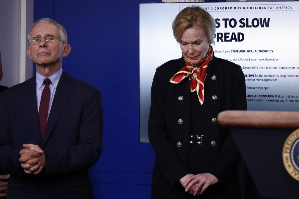 Drs. Deboarah Birx, the White House coronavirus response coordinator, Anthony Fauci, tge director of the National Institute of Allergy and Infectious Diseases, listen as President Donald Trump speaks during a news briefing on Tuesday. (ALEX BRANDON / Associated Press)
