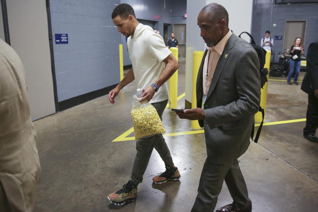 In this Sunday, April 24, 2016 photo, Golden State Warriors guard Stephen Curry carries popcorn as he limps out of the Toyota Center after Game 4 in the first round of the NBA playoff series against the Houston Rockets, in Houston. Golden State's record-setting run toward a second consecutive NBA championship may come down to an MRI on the sprained right knee of Stephen Curry. The NBA's reigning MVP missed the second half of a win over the Houston Rockets in Game 4 on Sunday and was expected to have the medical test later Monday. (Karen Warren/Houston Chronicle via AP)