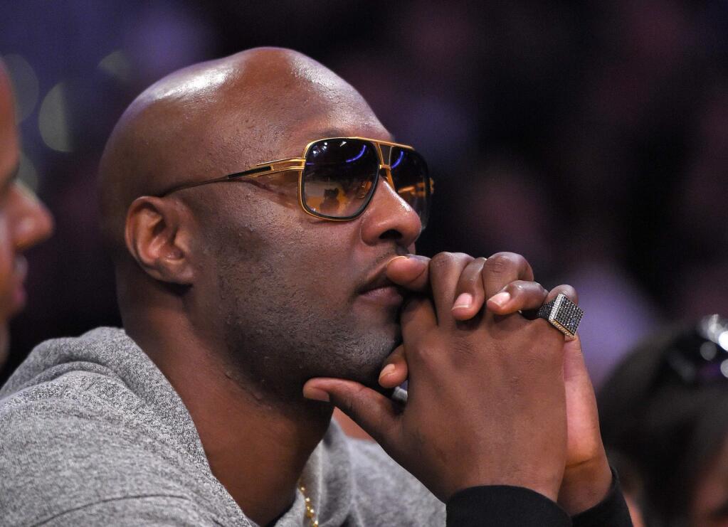 FILE - In this March 30, 2016, file photo, former Los Angeles Lakers' player Lamar Odom watches during the second half of an NBA basketball game between the Lakers and the Miami Heat in Los Angeles. Odom told Us Weekly for a story published online March 29, 2017, that he is “a walking miracle” after being found unconscious with cocaine in his system in a Nevada brothel in 2015. (AP Photo/Mark J. Terrill, File)