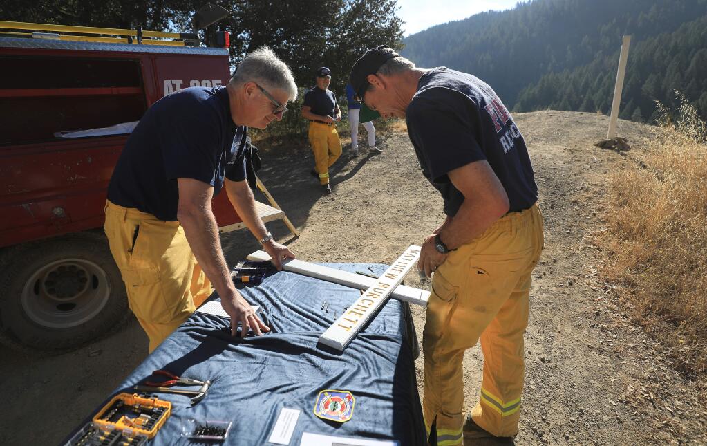 Lake Pillsbury firefighter Mark Linn, left and Mike Ullom, Tuesday, Aug. 13, 2019 prepare to put the finishing touches on a cross for Draper City, Utah firefighter Matthew Burchett, who was killed fighting the Ranch fire on the Mendocino Complex. The cross overlooks the Benmoore Creek drainage adjacent to the Eel River off Elk Mountain Road near the site where Burchett perished. (Kent Porter / The Press Democrat) 2019
