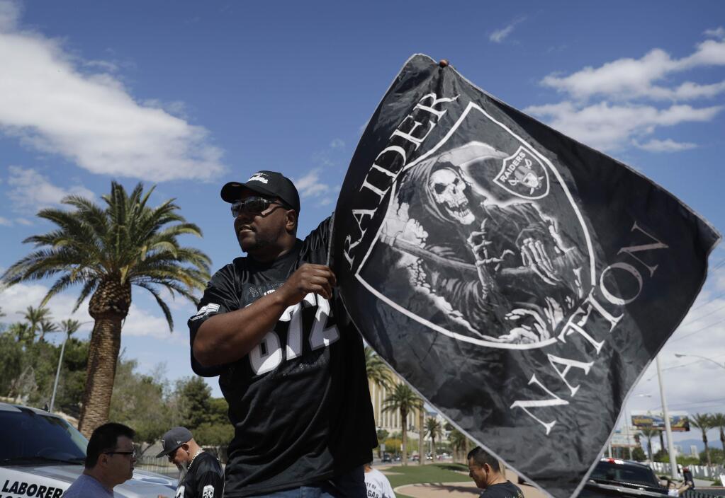 Ken Mclin holds up a Raiders banner Monday, March 27, 2017, in Las Vegas. NFL team owners approved the move of the Raiders to Las Vegas in a vote at an NFL football annual meeting in Phoenix. (AP Photo/John Locher)