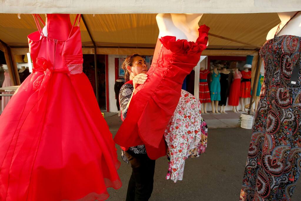 Blanca Caishpal, owner of Novedades Blanqui, takes down her storefront mannequin displays at the end of the day, in Santa Rosa, California, on Thursday, August 10, 2017. (Alvin Jornada / The Press Democrat)