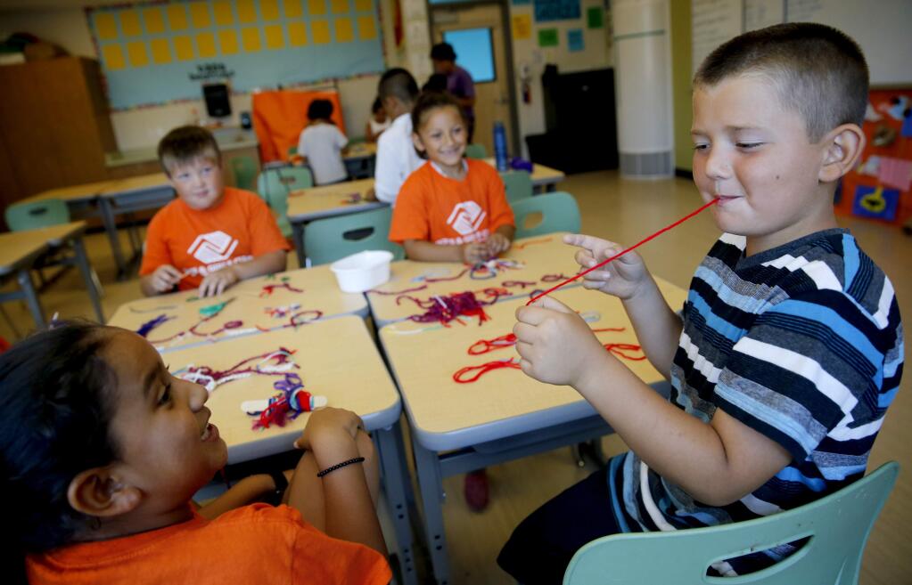Nathan Ponce, 7, right, pulls a string out of his mouth as he jokes around with Natalie Ruiz, 7, left, Joseph Beall, 8, and America Diaz, 7, during the Boys and Girls Clubs of Central Sonoma County summer camp at Roseland Creek Elementary School in Santa Rosa, on Tuesday, July 14, 2015. (BETH SCHLANKER/ The Press Democrat)