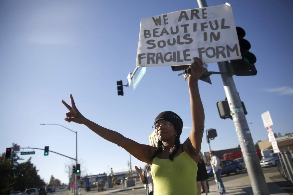 Kenyetta Todd holds up a sign during a gathering of people showing support for those targeted during the presidential campaign along Sebastopol Ave on Sunday, November 13, 2016 in Santa Rosa, California . (BETH SCHLANKER/ The Press Democrat)