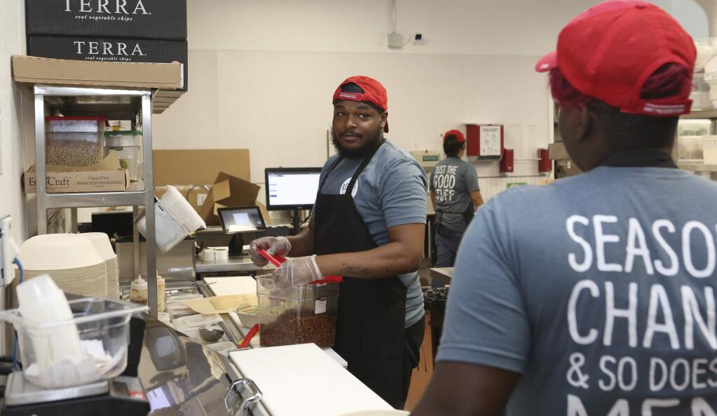 Workers in the B.Good ghost kitchen inside Kitchen United's Chicago, Ill., location prepare food for delivery on Aug. 29, 2019. Kitchen United, a start-up that builds kitchen commissaries for restaurants looking to enter new markets through delivery or take-out only, has plans to open 40 more kitchens in cities across the U.S. through 2020. (AP Photo/Teresa Crawford)