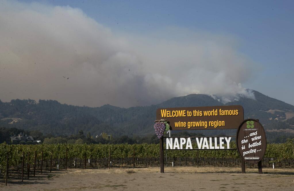 Smoke billows from a fire burning in the mountains over Napa Valley, Friday, Oct. 13, 2017, in Oakville, Calif. Firefighters gained some ground on a blaze burning in the heart of California's wine country but face another tough day ahead with low humidity and high winds expected to return. (AP Photo/Rich Pedroncelli)