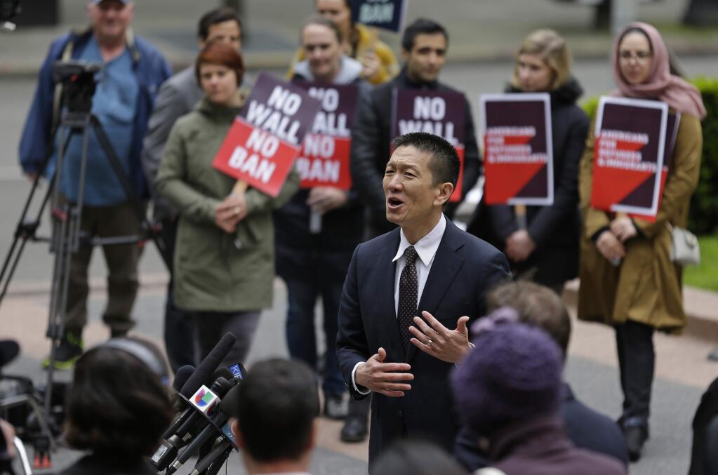 FILE - In this May 15, 2017, file photo, Hawaii Attorney General Doug Chin, center, talks to reporters outside a federal courthouse in Seattle. A U.S. appeals court on Monday, Nov. 13, allowed President Donald Trump's newest version of the travel ban to partially take effect. The decision 'closely tracks guidance previously issued by the Supreme Court,' Chin said in a statement. 'I'm pleased that family ties to the U. S., including grandparents, will be respected. We continue to prepare for substantive arguments before the Ninth Circuit on December 6 in Seattle.' (AP Photo/Ted S. Warren, File)