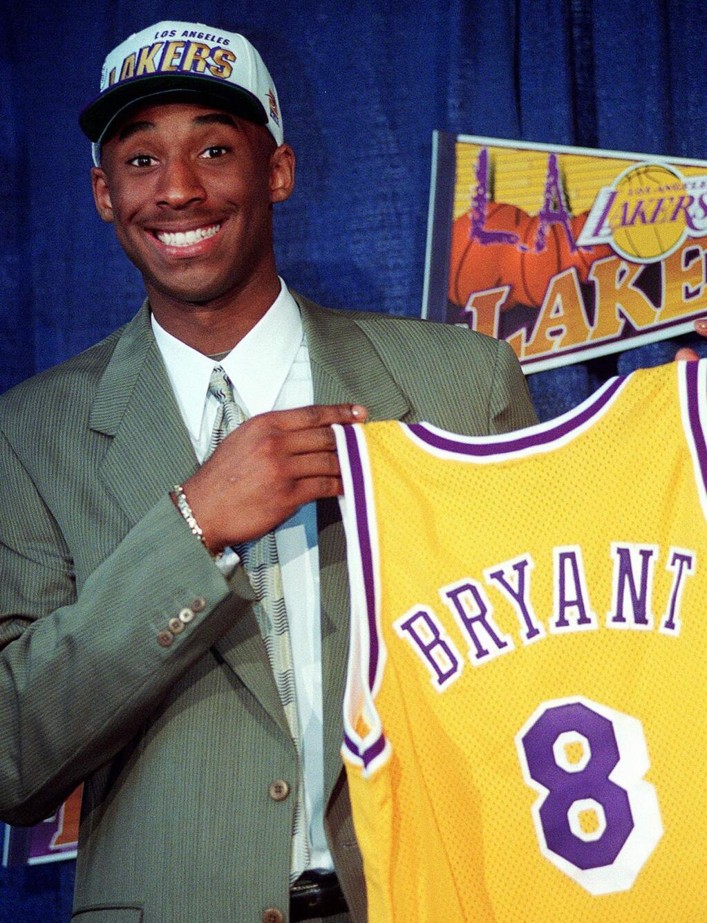 FILE - In this July 12, 1996, file photo Kobe Bryant, 17, jokes with the media as he holds his Los Angeles Lakers jersey during a news conference at the Great Western Forum in Inglewood, Calif. Bryant, a five-time NBA champion and a two-time Olympic gold medalist, died in a helicopter crash in California on Sunday, Jan. 26, 2020. (AP Photo/Susan Sterner, File)