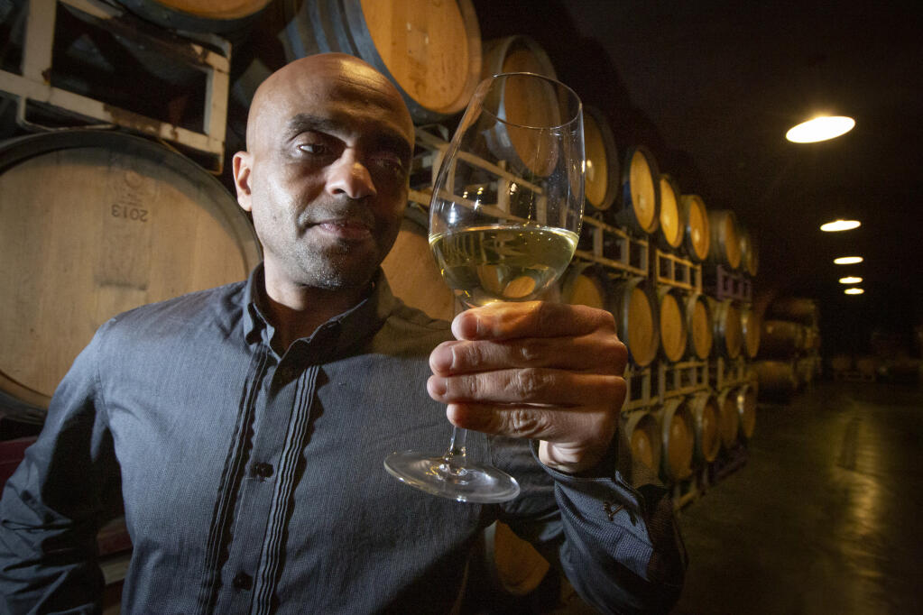 Winemaker Ayele Solomon, shown here at the Deerfield Ranch wine caves on Jan. 29, examines a glass of his honey wine, a type of wine historically made by every culture in the world, alongside barrels containing the beverage. (Photo by Robbi Pengelly/Index-Tribune)
