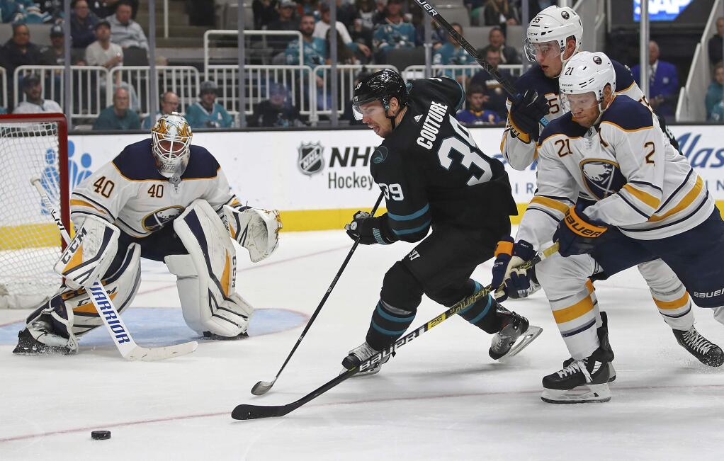 The San Jose Sharks' Logan Couture (39) moves the puck against Buffalo Sabres' Rasmus Ristolainen (55) and Kyle Okposo, right, in the third period hursday, Oct. 18, 2018, in San Jose. At left is Sabres goalie Carter Hutton. (AP Photo/Ben Margot)