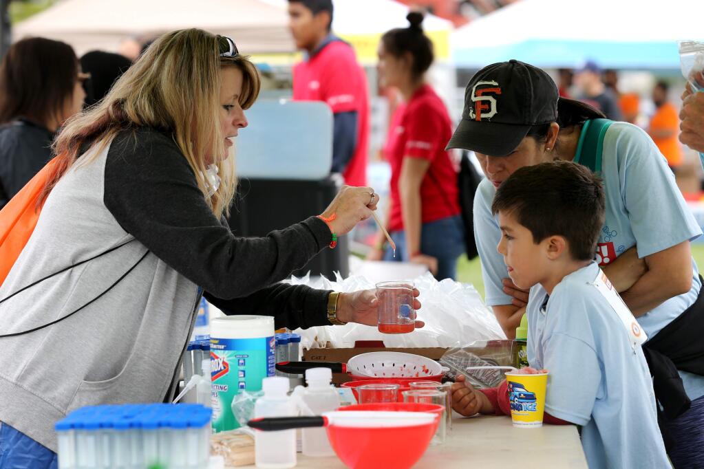 Volunteer Gina Rea, left, explains a strawberry DNA extraction experiment to Lucas Keiser, 7, and his mother Rocio during the 7th annual Sonoma County Kids Gran Fondo at Lucchesi Park in Petaluma, California on Sunday, August 18, 2019. (BETH SCHLANKER/The Press Democrat)