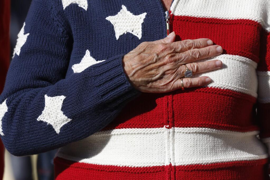 Carolyn Bellante puts her hand on her heart as the American flag passes by during the 2015 Veterans Day parade in Petaluma . (BETH SCHLANKER / The Press Democrat)