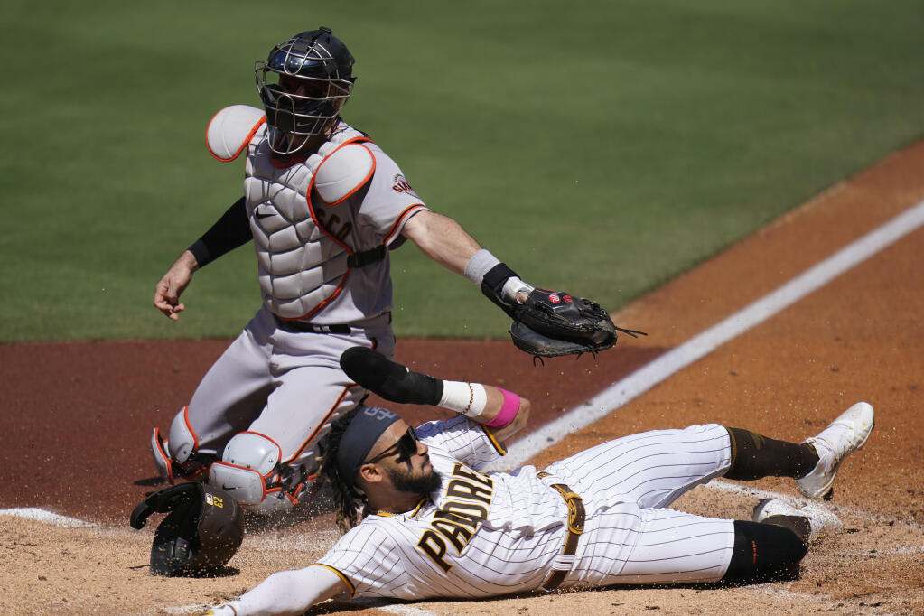 San Francisco Giants catcher Curt Casali, top, is late with the tag as the San Diego Padres’ Fernando Tatis Jr. scores from third off a sacrifice fly by Trent Grisham during the first inning on Thursday, Sept. 23, 2021, in San Diego. (Gregory Bull / ASSOCIATED PRESS)