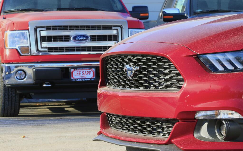 In this Jan. 13, 2015 photo, a Ford Mustang, right, is parked next to an F-150 pickup truck at the Lee Sapp Ford dealership in Ashland, Neb. With cheaper gasoline in the tank, some car dealers find they have too many smaller fuel-efficient cars, when trucks and sports cars might sell better. Lee Sapp, who runs the Ford dealership in Ashland, Neb., says that fluctuating gas prices will not necessarily make a person who thinks he needs an F-150 or wants an F-150 pickup truck, switch to a compact car. (AP Photo/Nati Harnik)