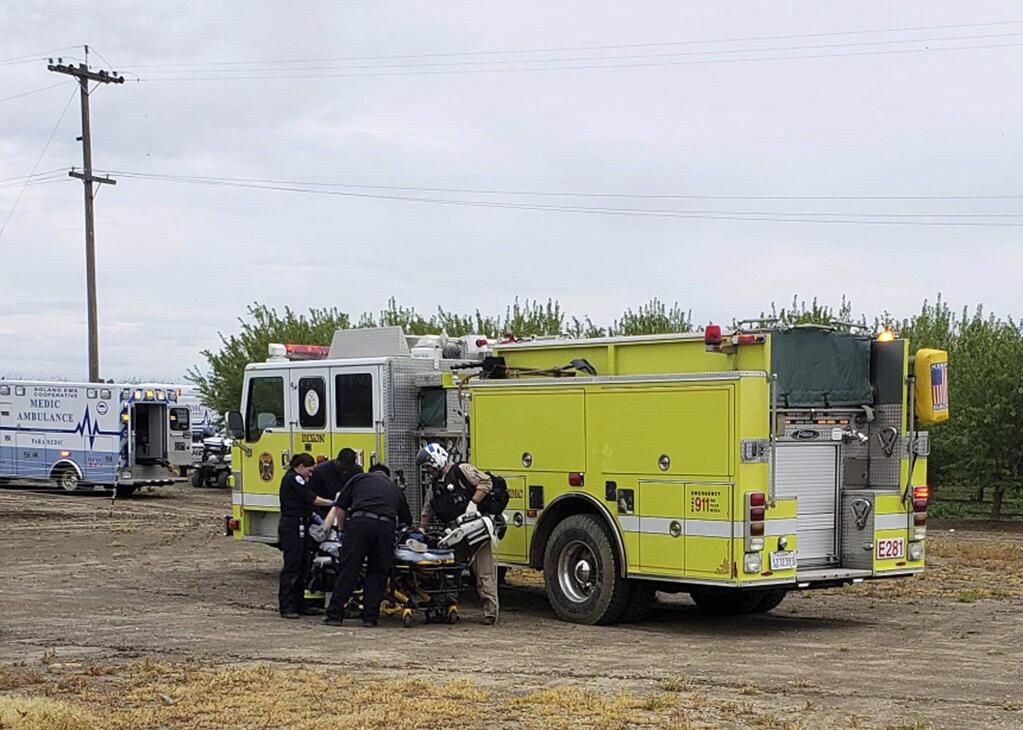 In this Monday, April 1, 2019, photo provided by the California Highway Patrol, fire and medical officials attend to one of two teenage boys who were electrocuted while trying to rescue a dog from an irrigation canal at an orchard in Dixon, Calif. KTXL-TV reported that the Solano County sheriff's office said that when the boys walked into the canal Monday to attempt to save the dog, one of the boys touched a nearby electrified gate. The boys were taken to a hospital where they died. (California Highway Patrol/Via AP)
