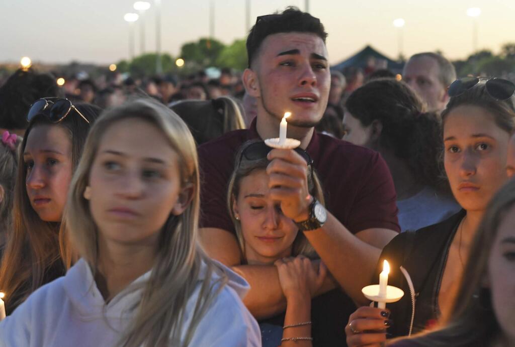 Mourners gather at a vigil that was held for the victims of the shooting at Marjory Stoneman Douglas High School, Thusday, Feb. 15, 2018, in Parkland, Fla. The teenager accused of using a semi-automatic rifle to kill more than a dozen people and injuring others at a Florida high school confessed to carrying out one of the nation's deadliest school shootings and concealing extra ammunition in his backpack, according to a sheriff's department report released Thursday. (Jim Rassol/South Florida Sun-Sentinel via AP)
