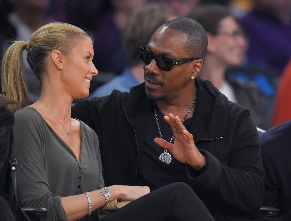 FILE - In this April 12, 2015, file photo, actor Eddie Murphy talks with his girlfriend Paige Butcher during an NBA basketball game between the Los Angeles Lakers and the Dallas Mavericks. Murphy and Butcher welcomed their first child together on May 3, 2016. (AP Photo/Mark J. Terrill, File)