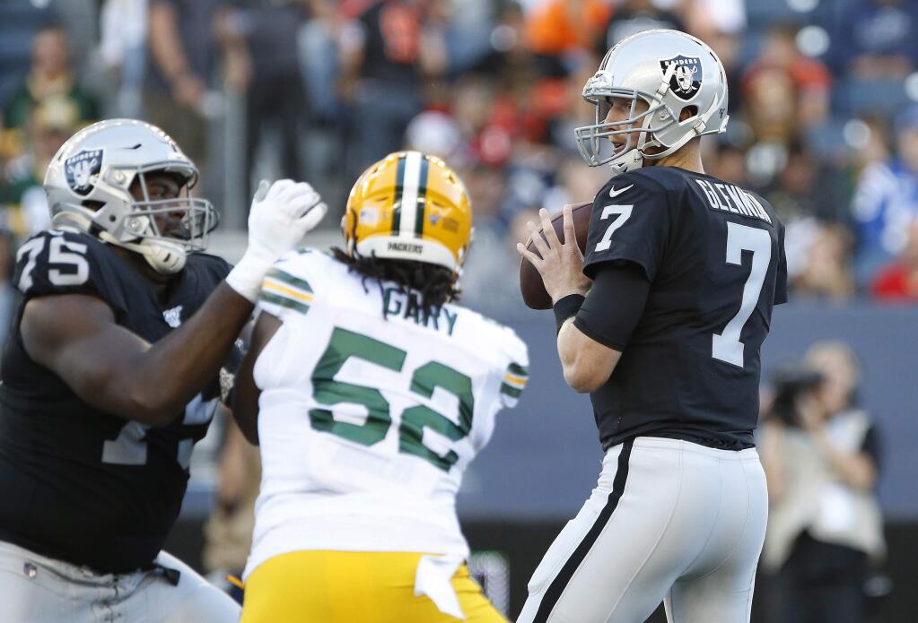 Oakland Raiders quarterback Mike Glennon looks for a receiver as the Green Bay Packers' Rashan Gary (52) defends during the first half Thursday, Aug. 22, 2019, in Winnipeg, Manitoba. (John Woods/The Canadian Press via AP)