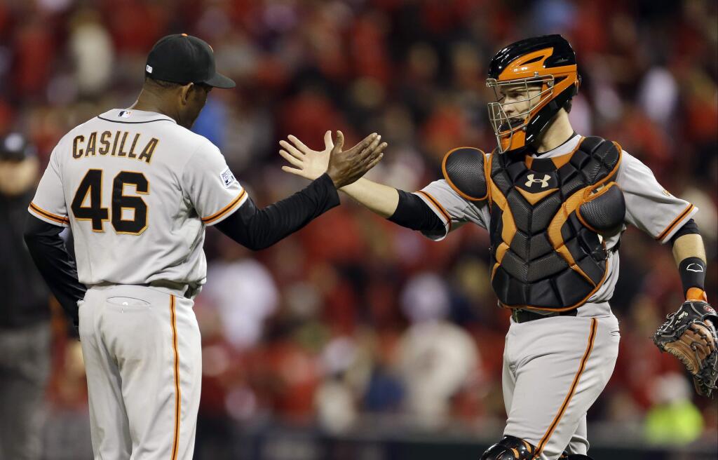 San Francisco Giants catcher Buster Posey celebrates with Santiago Casilla after Game 1 of the National League baseball championship series against the St. Louis Cardinals Saturday, Oct. 11, 2014, in St. Louis. The Giants won 3-0 to take a 1-0 lead in the series. (AP Photo/Jeff Roberson)