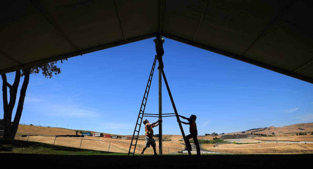 In preparation for June's NASCAR event at Sonoma Raceway, Jonathan Rodriguez, left, and Kevin Samayoa of Special Event Work Solutions steady a support beam as Jose Samayoa bolts it to a larger tent structure, Wednesday, May 12, 2021 in Sonoma along the straightaway to turn two. (Kent Porter / The Press Democrat) 2021