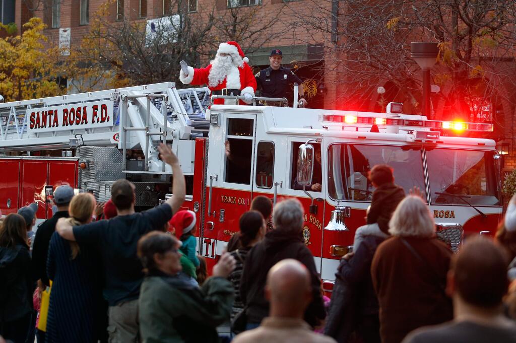 Santa Claus waves as he arrives aboard Santa Rosa Fire Department's Truck 1 during Winterlights at Old Courthouse Square in Santa Rosa, California on Friday, November 24, 2017. (Alvin Jornada / The Press Democrat)