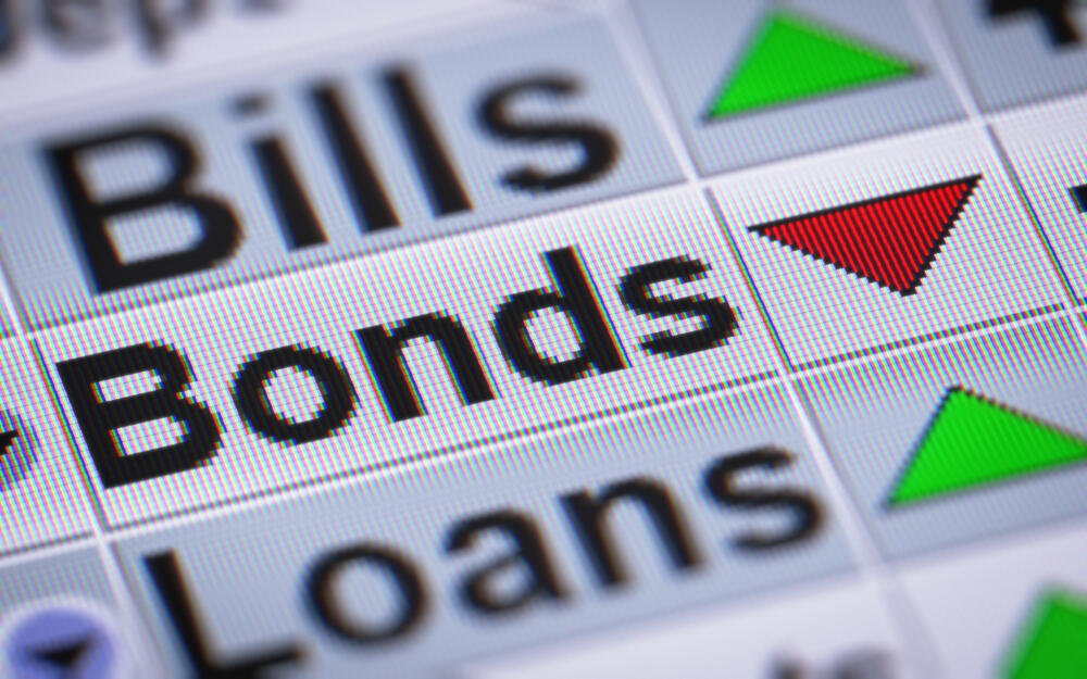 Closeup of a computer screen shows a red down-pointing arrow indicator next to “bonds,” communicating a decrease in value.