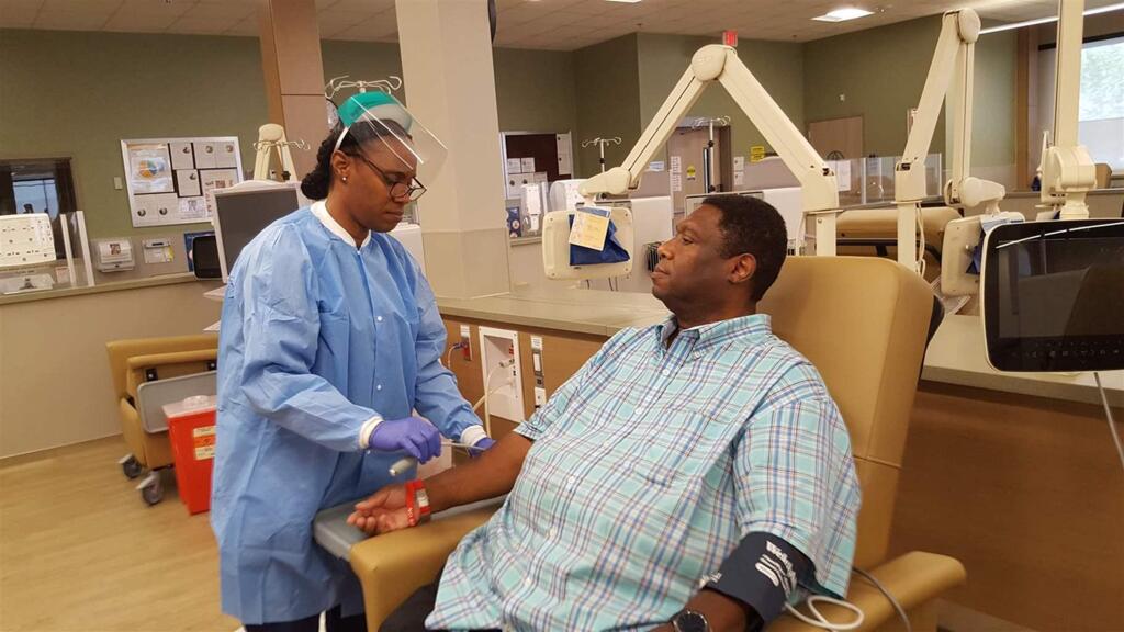 Dialysis technician Audrey Thomas demonstrates how kidney dialysis is set up on patient DeWayne Cox at a Southern California clinic. (ELAINE S. POVICH / Pew Charitable Trusts)