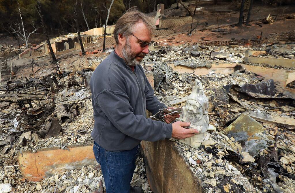Hans Dippel sorts through the remains of his fire ravaged home on Chateau Ct. in Santa Rosa. One of the few unscathed items he found was a gnome given to him as a symbol of protection for the home when moved into the house off Parker Hill Rd. (photo by John Burgess/The Press Democrat)