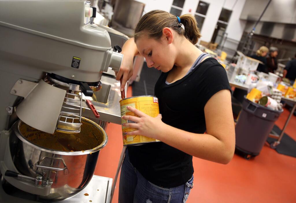Kati Hilario, 15, scoops pumpkin filling into an industrial mixer in the kitchen at the Redwood Empire Food Bank, in Santa Rosa on Tuesday, Nov. 25, 2014. Hilario is baking 146 pies that she sold to benefit the food bank. (CHRISTOPHER CHUNG/ PD)