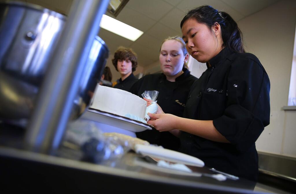 Tiffany Liang, right, frosts a cake while getting advice from Hannah Quackenbush in their catering and hospitality class at Maria Carrillo High School, in Santa Rosa, on Friday, January 27, 2017. (Christopher Chung/ The Press Democrat)