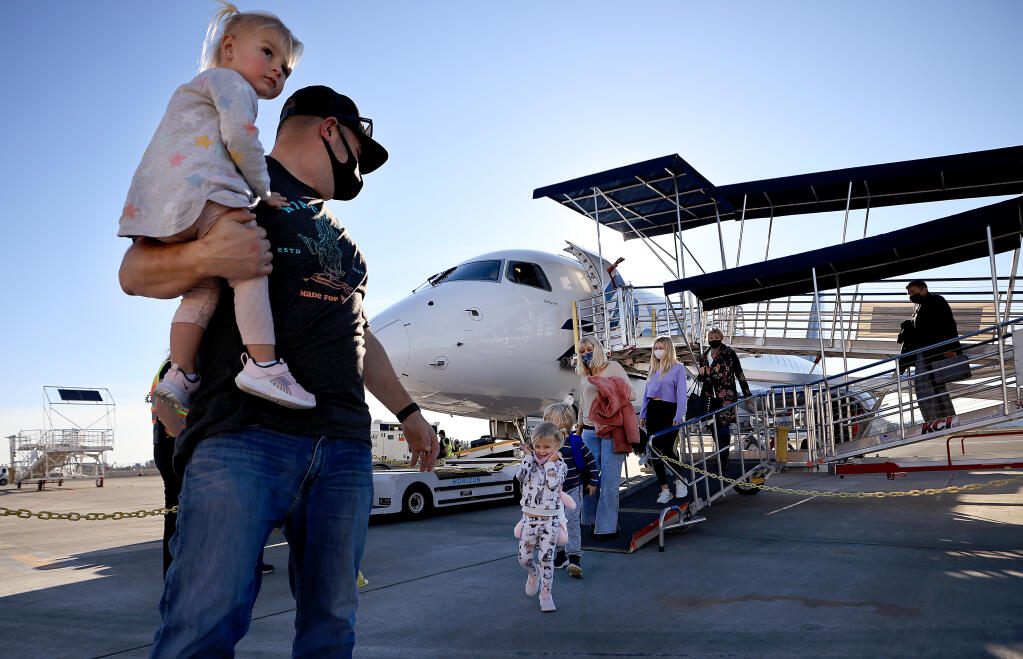 Flying in from Southern California to see relatives in Sonoma County for Thanksgiving are Aron Rainone with daughter Daizy, on shoulders and, from front, Zoey, in pink, Hendrix, Paula Mason and Sara Rainone, Tuesday, Nov. 23, 2021 at the Charles M. Schulz Sonoma County Airport.  (Kent Porter / The Press Democrat) 2021