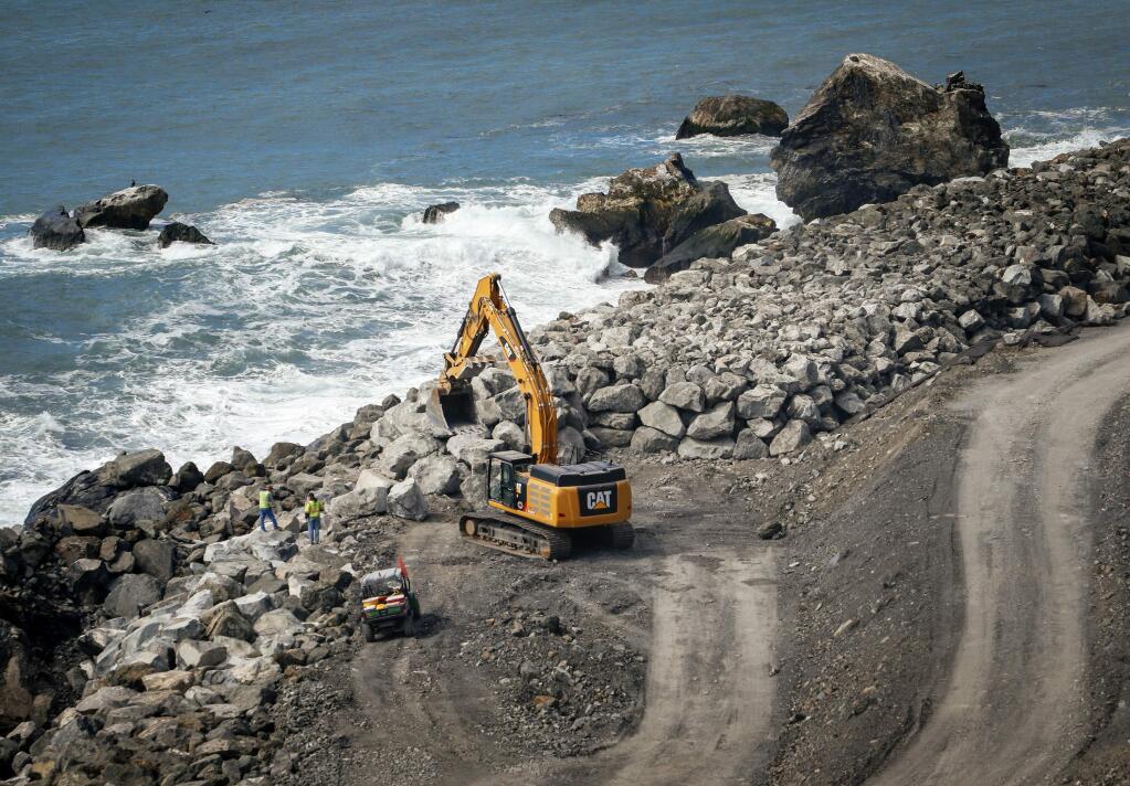 FILE - In this March 8, 2018, file photo, crews work to finish up a massive seawall at the base of the Mud Creek Slide alon Highway 1 on the coast of Big Sur, Calif. Transportation officials say the stretch of Highway 1 in the scenic Big Sur coastal region that was blocked last year by a massive landslide is ready to be used. The California Department of Transportation says the road that connects Los Angeles to San Francisco will be open to all travelers by mid-morning Wednesday, July 18, 2018. (Joe Johnston/The Tribune (of San Luis Obispo) via AP, File)