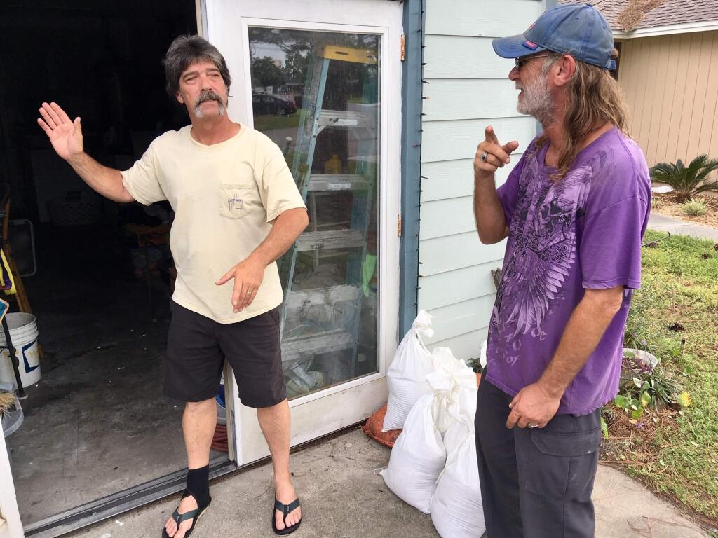 Dwight Williams, left, and Timothy Thomas discuss whether to evacuate their neighborhood in Panama City Beach, Fla., on Tuesday, Oct. 9, 2018. Thomas figures he and his wife will be safe from rising ocean water since they live in a second-story apartment. Others also aren't leaving, and a bar along the beachfront road threw a hurricane party less than 2 miles away from Thomas' home as Michael pushed toward shore Tuesday night. (AP Photo/Jay Reeves)